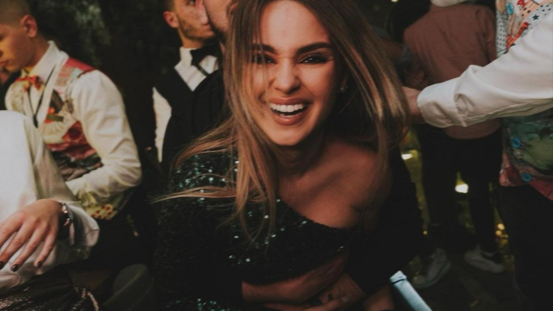 A woman laughing joyfully at a lively night-time celebration